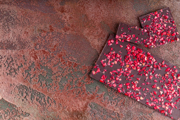 Handmade Chocolate with Berries with Pieces of Dried Strawberries Lies a Stack on a Brown Marble Background. Top view