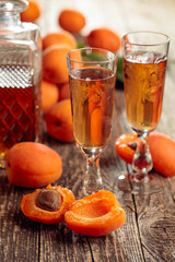 Apricot liquor and fresh apricots on a old wooden table.