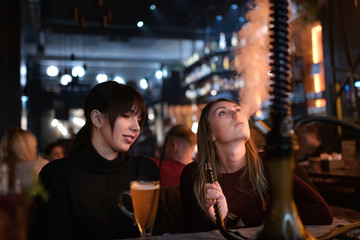 Girlfriends smoking hookah at shisha bar at holidays.