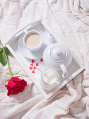Close up of cup of tea with red rose on the white tray