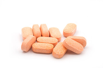 Pile of orange pills of vitamins on white background