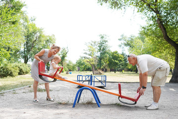 Fototapeta premium Grandparents with grandchild enjoying the sunny day in the park
