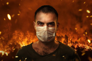 A man in a medical mask to protect the cuts of breath against the backdrop of severe forest fires....