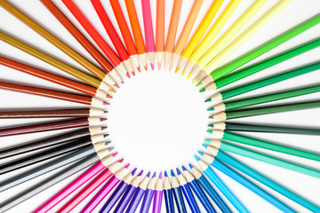 Group of mixed colourful pencils arranged in circle and isolated on white, children school or office suppliers photographed with soft focus from side view, with space for text