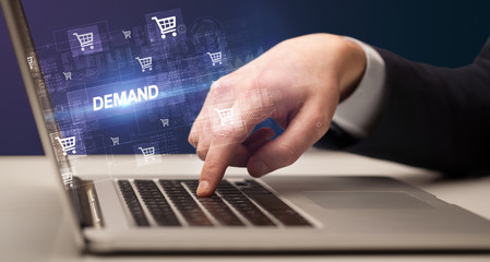 Obraz na płótnie Canvas Businessman working on laptop with DEMAND inscription, online shopping concept