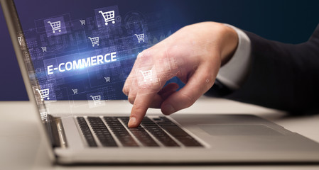 Businessman working on laptop with E-COMMERCE inscription, online shopping concept
