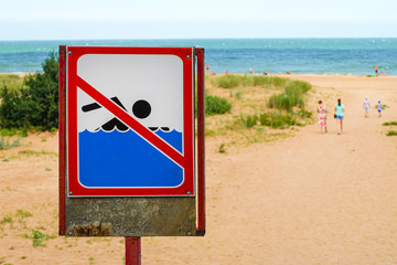 Sign prohibiting swimming in sea. Sign no swim standing on beach.