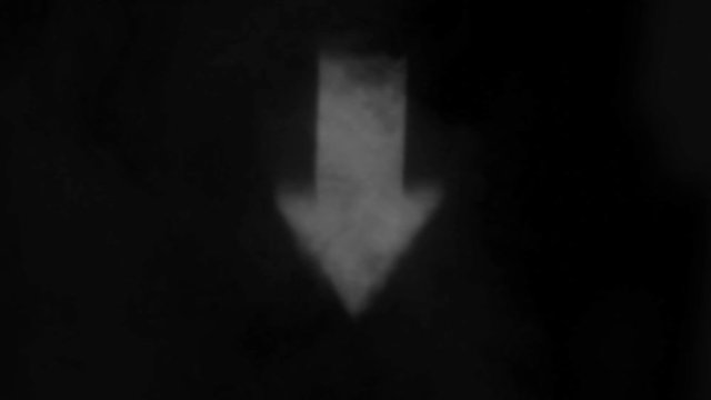 Fuzzy and highly blurred sign with a downward arrow projected onto the smoke