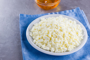 Cottage cheese and honey. Fresh cottage cheese on a gray background. Homemade curd on a blue napkin on cement background. Top view. Copy space