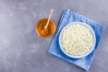 Cottage cheese and honey. Fresh cottage cheese on a gray background. Homemade curd on a blue napkin on cement background. Top view. Copy space