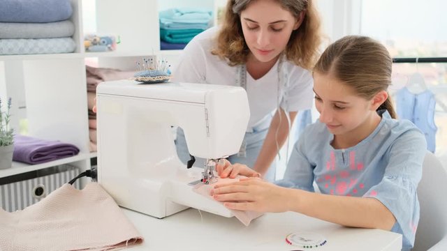 Seamstress teaching school girl to sew in class