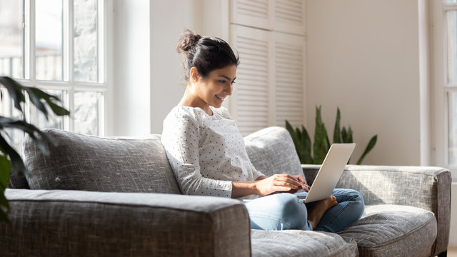 Happy indian girl using modern laptop at home - Powered by Adobe