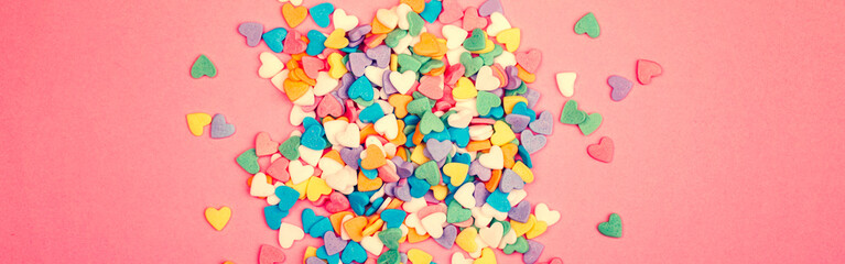 Fototapeta na wymiar Happy Valentine Day. Beautiful card wallpaper with colorful hearts candies on pink coral background. Concept of love. February holiday. Web banner header for website.