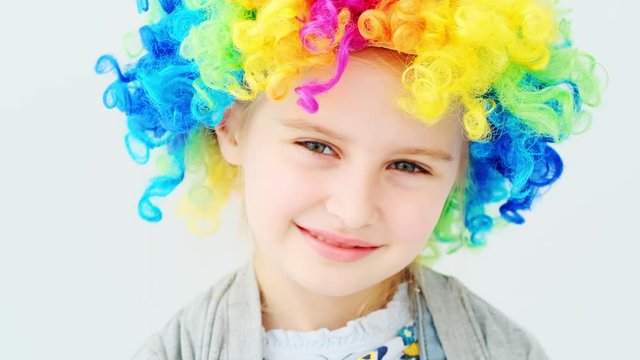 Cute cheerful girl in colored wig looking straight in camera
