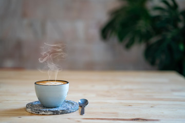 Cup coffee with smoke on wooden table.