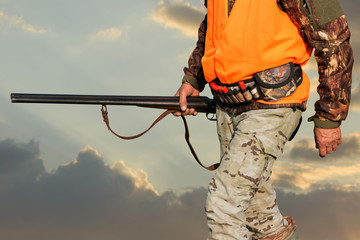 Silhouette of a hunter on the background of the morning red dawn. Stands at the ready with a gun.