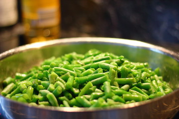 Green beans in a steel pan on a dark background.