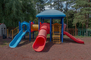 Children's playground and colorful slides next to the forest.