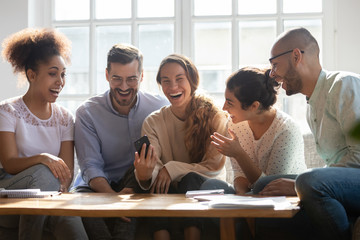 Overjoyed young people have fun using cellphone together