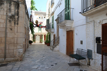 Fototapeta premium Street in Locorotondo town, Italy, region of Apulia, Adriatic Sea - colorful fabric octopus hanging above the street