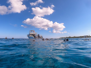 Naklejka premium Scuba divers in ocean near dive boat on clear calm sunny day with blue sky