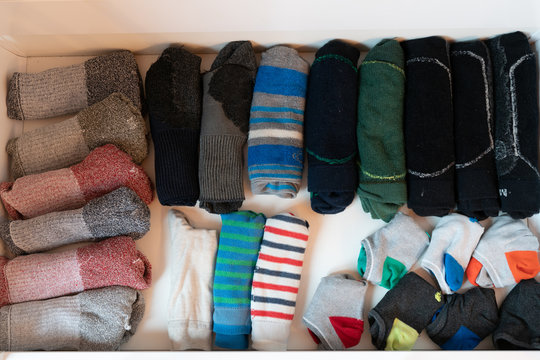 Many Colorful Men's Socks In A Plain White Wooden Sock Drawer