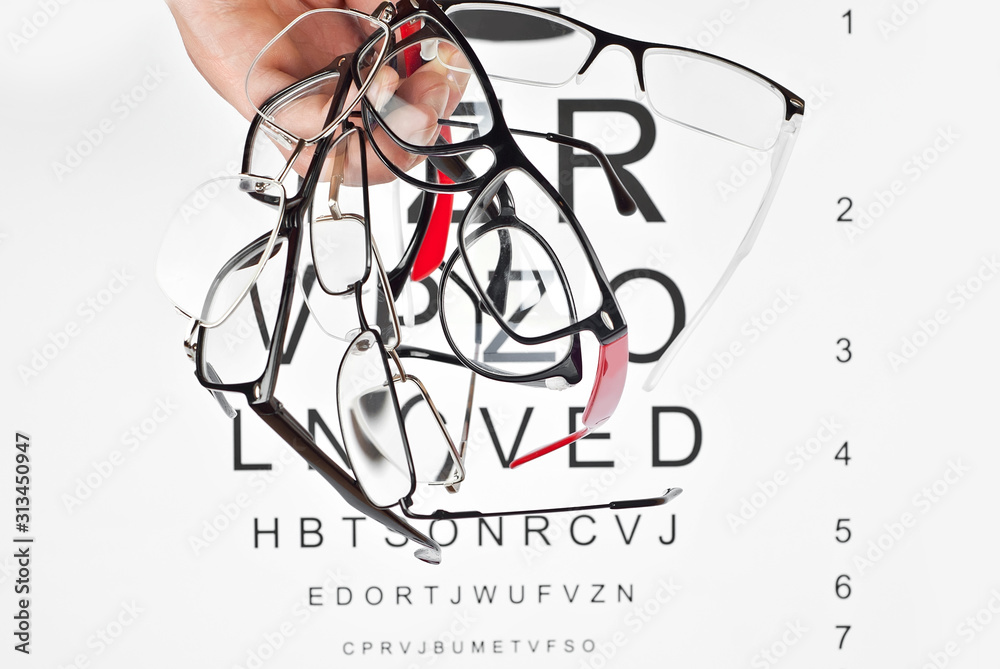 Poster glasses on a white background. background with letters for vision test. many glasses in hand.