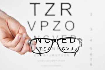 Glasses on a white background. Background with letters for vision test. Text and glasses are...