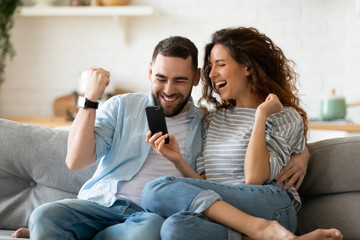 Excited couple holding smartphone celebrating online lottery win - obrazy, fototapety, plakaty
