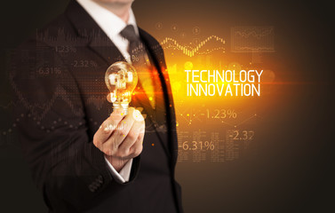 Businessman holding lightbulb with TECHNOLOGY INNOVATION inscription, Business technology concept