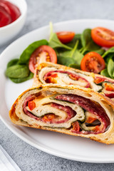 Italian food Pizza roll stromboli with cheese, salami, spinach and red pepper a light background.