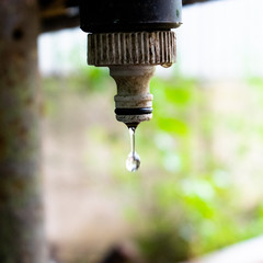 A water drop falls from a dirty and rusty water tap - Water engineering theme