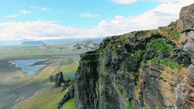 Aerial: Volcanic terrain of Iceland from above with black sandy beaches. Recorded at Dyrh&oacute;laey Lighthouse.
