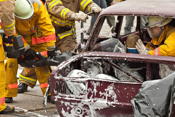 Demonstration of rescue work. Firefighters break into a car after an accident. Rescue team retrieve the victim from the burned car. Training firefighters.