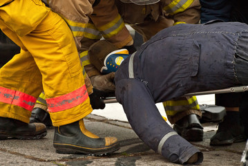 Demonstration of rescue work. Firefighters break into a car after an accident. Doctors in the background are preparing to provide first aid.