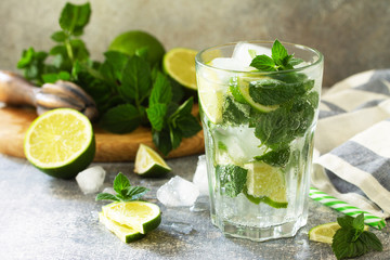 Summer cold drink and cocktail. Fresh Mojito cocktail with lime, ice and mint in a glass on a gray stone background.