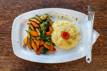 Mashed potatoes with fried vegetables on a white plate.