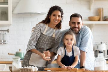 Family cooking together in kitchen smiling looking at camera