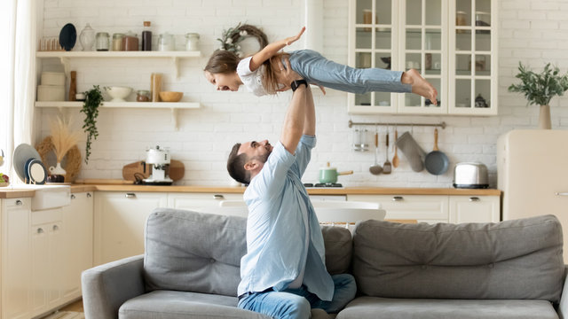 Father Holding Lifting Cheerful Daughter Having Fun At Home