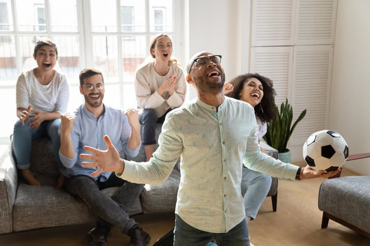 Overjoyed multiethnic friends watch football at home