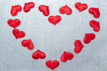 red hearts laid out in the shape of a big heart on a silver background, with copy space