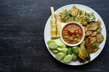 Shrimp paste and vegetables on black tiled table. 