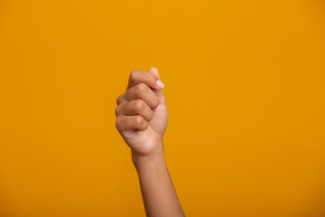 Woman hand holding something on yellow background, closeup of hand.