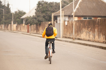 A country boy in a yellow sweater rides an old bicycle on a rural road.