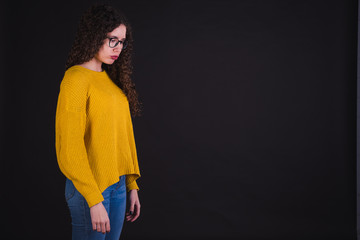 Young girl model posing with yellow t-shirt and blue pants in black background