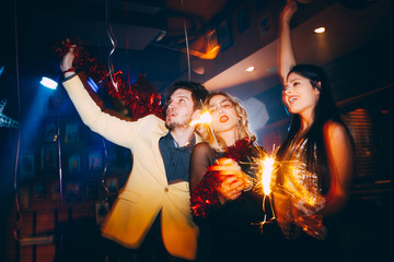 Three friends having fun and holding sparklers at New Year's party