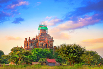 Colorful sky above temples surrounded by green vegetation in old Bagan, Myanmar.