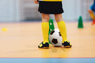 Football futsal training for children. Indoor soccer young player with a soccer ball in a sports...