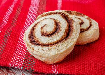 Traditional homemade cinnamon buns on a red tablecloth.
