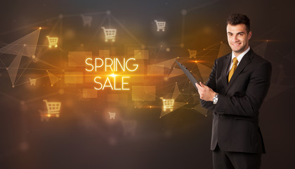 Businessman with shopping cart icons and SPRING SALE inscription, online shopping concept